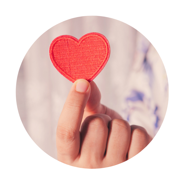 A person holding up a red heart shaped patch.